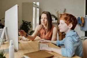 mother pointing at a computer while her son watches